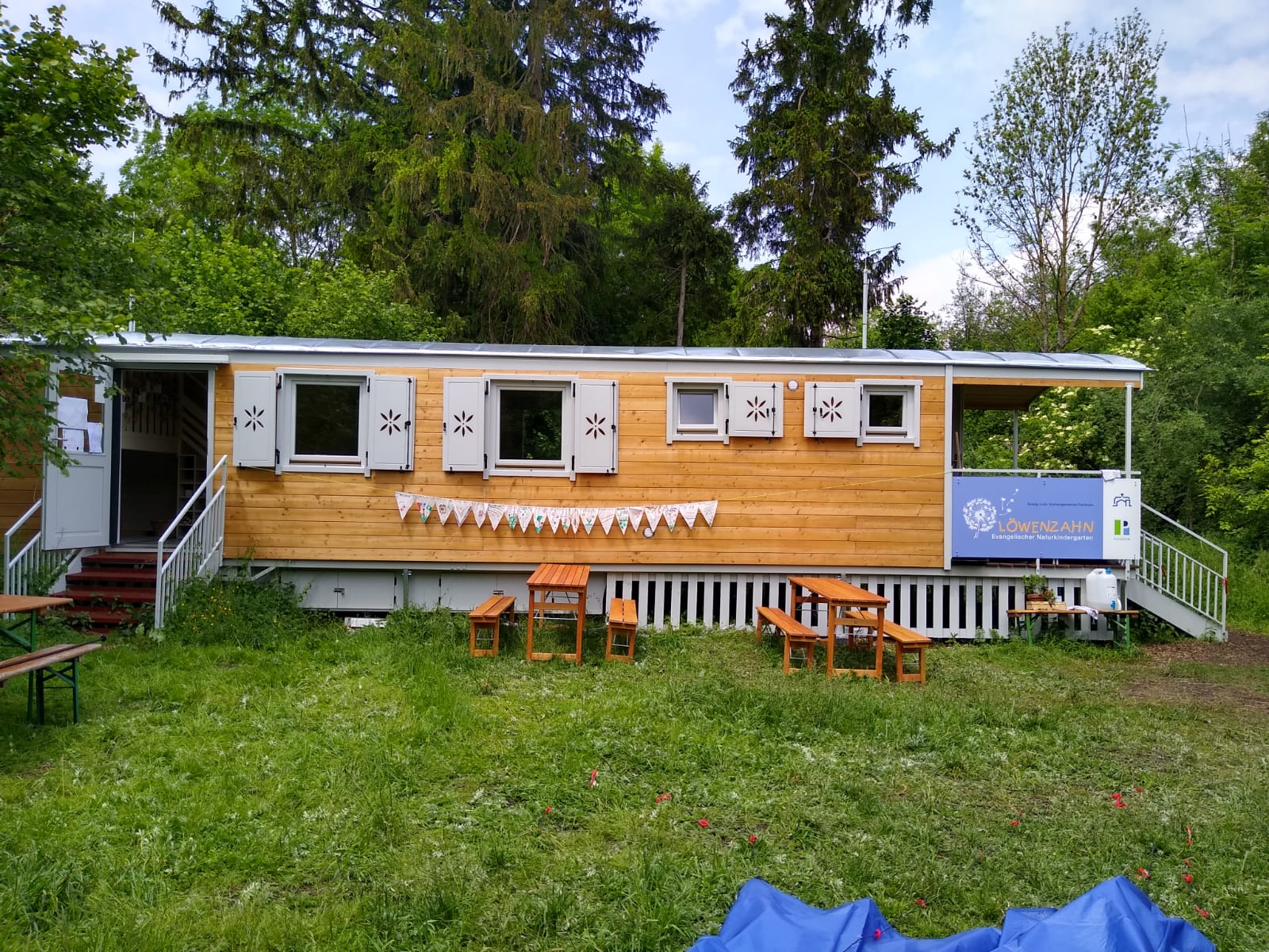 Ein Waldkindergartenwagen auf einer grünen Wiese.
