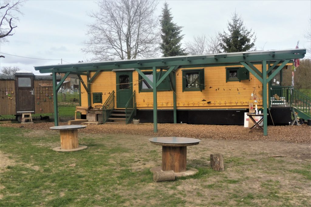 Waldkindergartenwagen aus Holz mit grünen Akzenten und einer grünen Seitenüberdachung