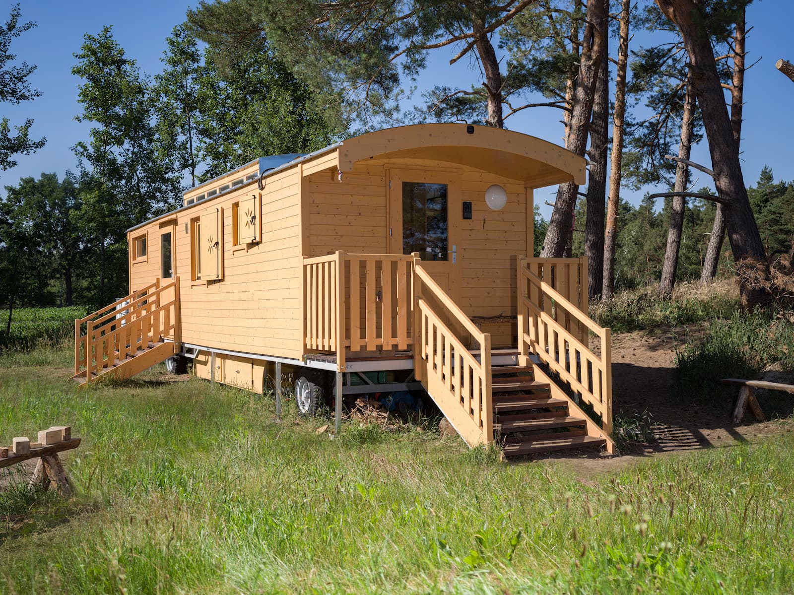 Bauwagen steht im Sommer auf einer Wiese unter Bäumen und sieht aus wie ein Kindertraum von einer Schutzhütte