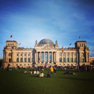 Blick von vorne auf den deutschen Bundestag bei blauem Himmel.