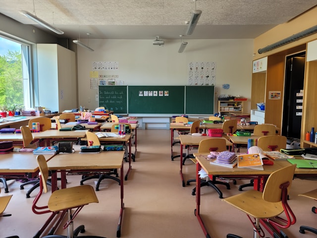 Blick in eine leere Schulklasse. Es liegen Schulmaterialen auf den Tischen.